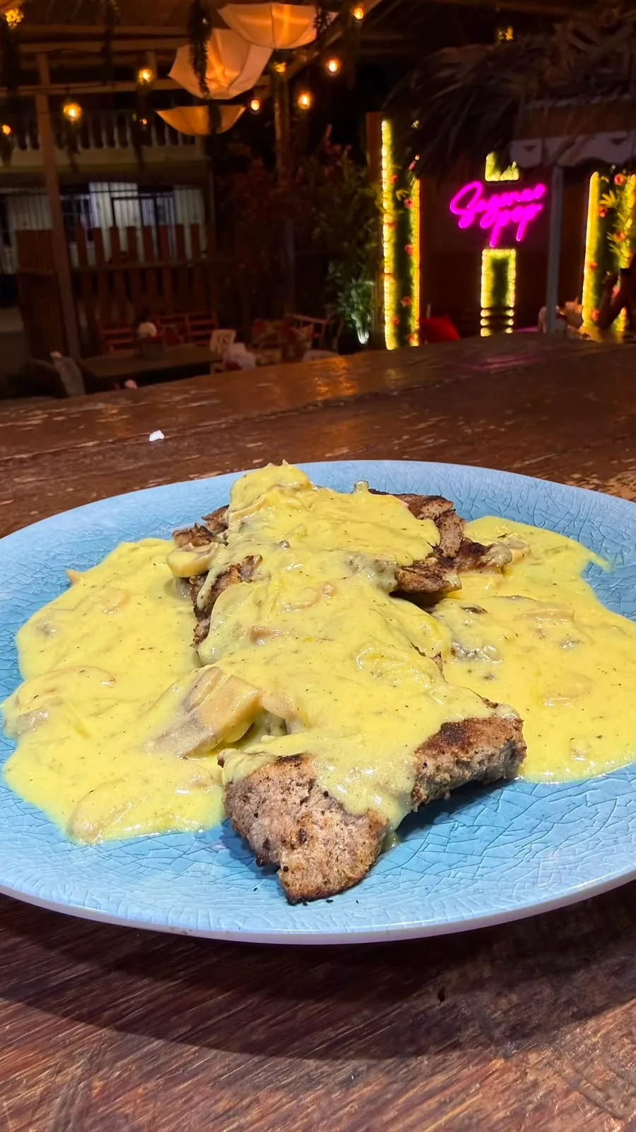 Carne a la parrilla en salsa cremosa de champiñones, en un plato azul.