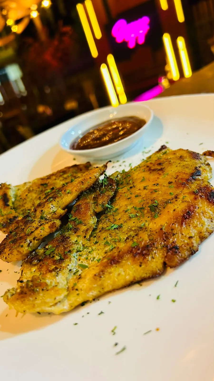 Filete de pescado a la parrilla con especias y salsa para acompañar.
